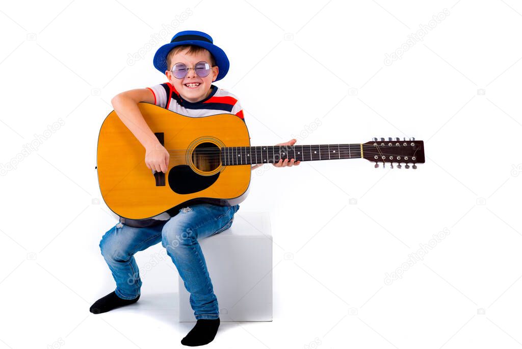 A boy kid plays guitar on a white background in the studio.