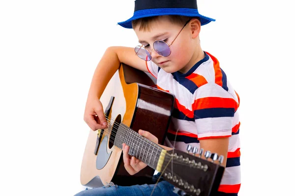 A boy kid plays guitar on a white background in the studio.