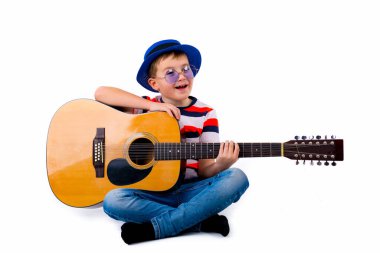 Stüdyoda beyaz bir arka planda gitar tutan bir çocuk..