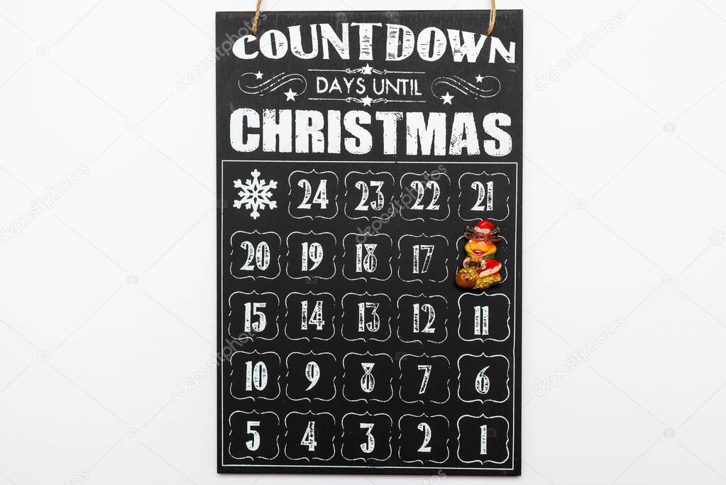 Toy bull on black wooden advent calendar showing Christmas countdown top view flat lay white background.