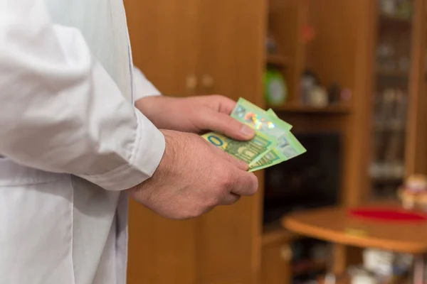 Doctor counting money 100 Euro banknotes. Paid medical services healthcare concept.