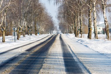Güneşli bir günde, karlı ormanda kış yolu..