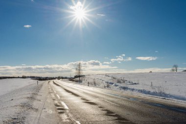 Mavi gökyüzünün altında kış yolu, güneş. Güzel kırsal yol asfaltı..