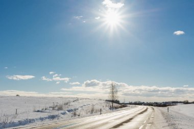 Mavi gökyüzünün altında kış yolu, güneş. Güzel kırsal yol asfaltı..