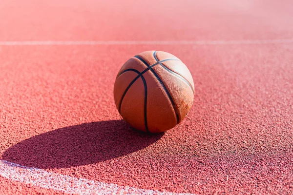 Orange ball for basketball lying on the sport court.Sport red court outdoor.