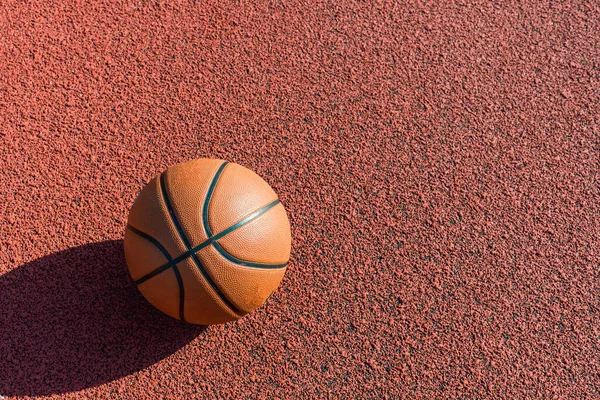 Orange ball for basketball lying on the sport court.Sport red court outdoor .Copy space.Top view.