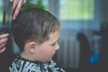 Berber dükkanında saç tıraşı olan sevimli bir çocuk. Yakından. Tonlanmış..