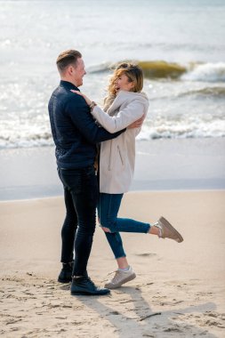 Genç çift kumların üzerinde eğleniyor ve eğleniyorlar. Yaz, bahar, sonbahar tatili..