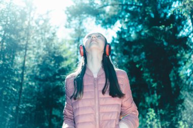 Sevimli, neşeli, sıska, eğlenen, ormanda müzik dinleyen yaz, bahar ormanı ya da park manzaralı bir genç kız. Yaklaştın..