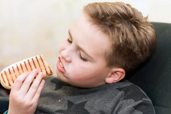 家の子供にホットドッグを食べる空腹の少年は ホットドッグのサンドイッチを食べます — ストック写真