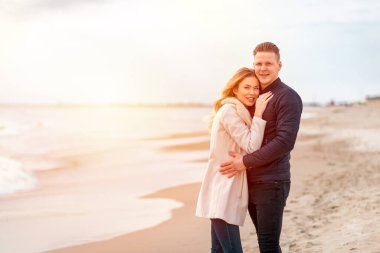 Tropik sahilde gün batımında güzel romantik bir çift. Ve deniz kıyısında sarılıyorlar..