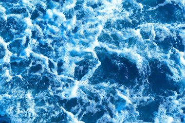 Derin mavi ve dalgalı deniz manzarası, bol bol deniz spreyi. Mavi arka plan. Odaklanma, bulanık görüntü..