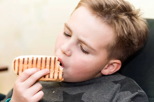 家の子供にホットドッグを食べる空腹の少年は ホットドッグのサンドイッチを食べます — ストック写真