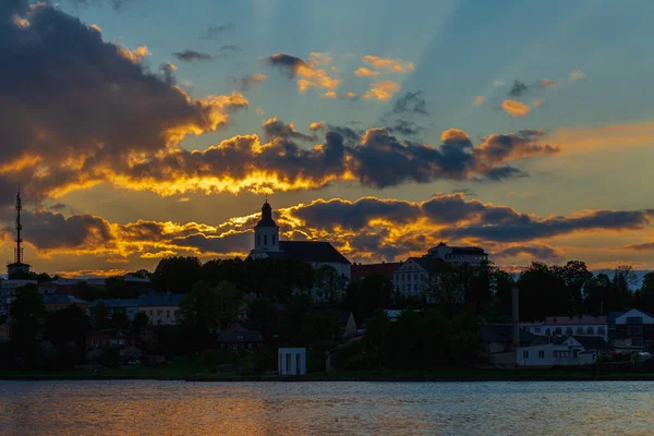 Town sea coast at the sunset evening.Sun rays passing through storm clouds over the lake bay town. Urban image.Golden hour.