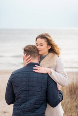 Baharda plajda genç ve şık bir çift. Birbirinize sarılın ve sıcak bir bahar akşamının tadını çıkarın..