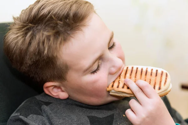 家の子供にホットドッグを食べる空腹の少年は ホットドッグのサンドイッチを食べます — ストック写真