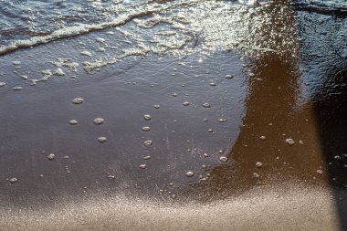 Kumlu akşam kumsalında denizin yumuşak dalgası. Odaklanma, bulanık görüntü. Boşluğu kopyala.