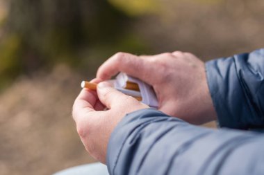 Yakından çekilen kişi karton sigara kutusundan bir sigara seçer. Açık hava fotoğrafı..