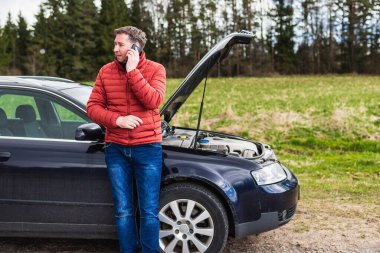 Araba bozulduktan sonra tamirciyi arayan adam. Yolda cep telefonuyla konuşan adam. arızalı araba.