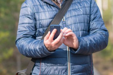 40 'lı yaşlarda cep telefonlu bir adam bahar ormanlarında sinyal arıyor..