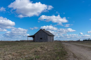 Tarlalarda terk edilmiş eski bir ahşap ev gökyüzü bulutları, bir yol ahırı ya da korkunç bir konsept yanında.