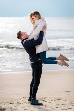 Genç çift sahilde eğleniyor ve eğleniyor. Bahar, sonbahar, sonbahar tatili..