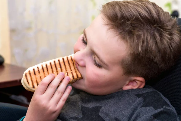 家の子供にホットドッグを食べる空腹の少年は ホットドッグのサンドイッチを食べます — ストック写真