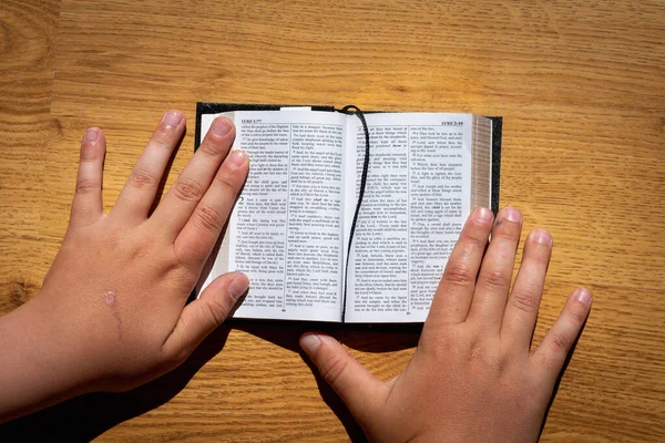 Childs Hands Hold Bible Leaning Wooden Table Small Book Holy — Stock Photo, Image