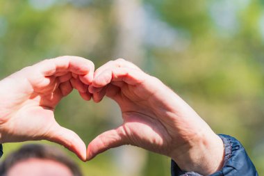 Güneşli bir günde, ormanda elleri dışarıda, kapalı bir kalp..