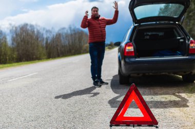 Çekici adam ellerini kaldırır ve yolda arabasıyla sorun yaşar. Kırsal yolda sorun yaşayan adam. Acil durum işaretine odaklan..