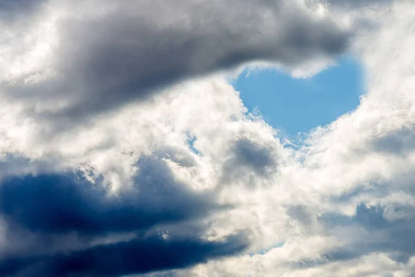 Heart shape white fluffy clouds in the blue sky background.Blue cloudy heart shape white sky in the nice blue heaven sky.