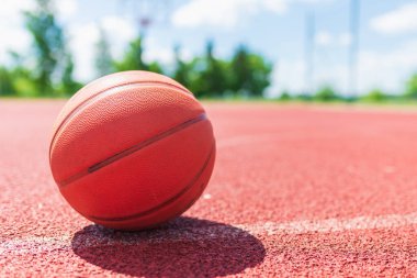 Kırsal kesimde kırmızı şehir basketbol sahası turuncu eski basketbol sahası. Güneşli yaz sıcağı. Arka plan bulanıklığı. Turuncu top oyuncuyu bekliyor..