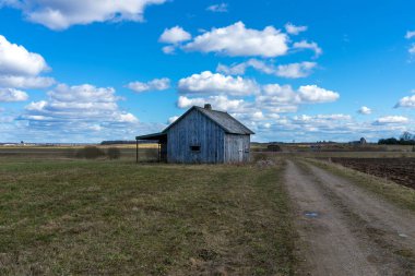 Tarlalarda terk edilmiş eski bir ahşap ev gökyüzü bulutları, bir yol ahırı ya da korkunç bir konsept yanında.