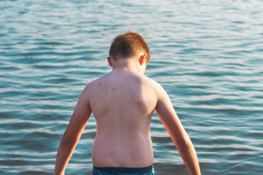 Tatlı bir çocuk, sıcak gün batımında gölde veya sahil suyunda eğlenmeyi sever. Kırsal alanda çocukluk tatiliniz kutlu olsun..
