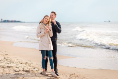 Genç çift sahilde eğleniyor ve eğleniyor. Bahar, sonbahar, sonbahar tatili..