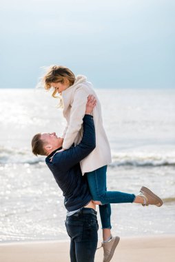 Genç çift sahilde eğleniyor ve eğleniyor. Bahar, sonbahar, sonbahar tatili..