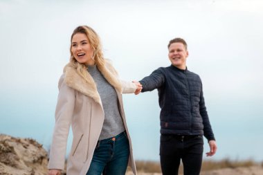 Beni takip edin. Romantik bir kavram. Dışarıda uzun sarı saçlı genç bir kadın erkeğin elini tutuyor. Birlikte seyahat ediyorlar. Kız güzel gülümsüyor..