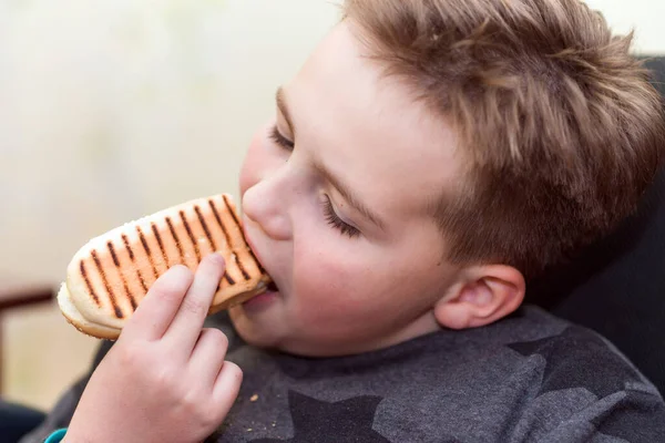 家の子供にホットドッグを食べる空腹の少年は ホットドッグのサンドイッチを食べます — ストック写真