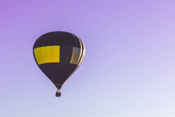 紫色の空に熱気球が飛びます 紫色の澄んだ空に青い黄色の熱気球が一つ — ストック写真