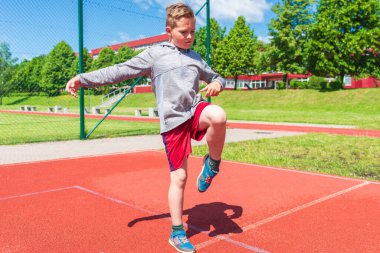Basketbolcu çocuk sahada esneme hareketleri yapıyor. Çocuk ısınıyor. Güneşli bir günde Red Court Sokağı 'nda..