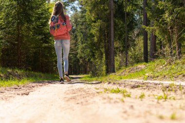 Sırt çantalı genç bir kız turist yaz günü ormanda yürüyor. Hipster yaşam tarzı ve tek kişilik gezi..
