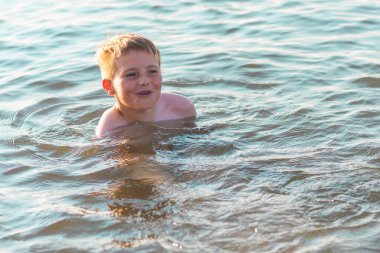 Mutlu gülümseyen çocuk suda yüzerken eğleniyor. Tatlı çocuk suda yüzüyor. Çocuk sahilde eğleniyor. Yaz tatili. Aktif yaşam tarzı konsepti. Yaz tatilindeki mutlu çocuk..