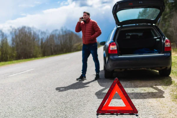 Man calling repair service after car breakdown.youg man talking on cell mobile phone on road. broken car situation.Outdoors shot.