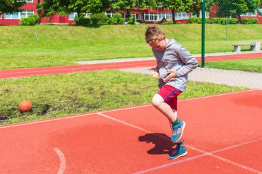 Basketbolcu çocuk sahada esneme hareketleri yapıyor. Çocuk ısınıyor. Güneşli bir günde Red Court Sokağı 'nda..