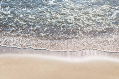Kumlu sahilde denizin yumuşak dalgası. Odaklanma, bulanık görüntü. Boşluğu kopyala.