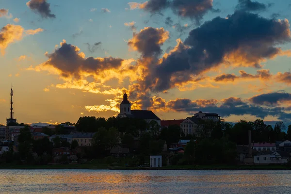 Town sea coast at the sunset evening.Sun rays passing through storm clouds over the lake bay town. Urban image.Golden hour.