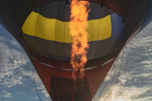 Hot flame from a gas burner light up inside of a hot air balloon at summer evening.