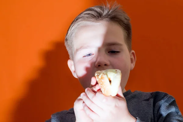 ハンサムな10歳の男の子が熱い犬を屋内オレンジのスタジオの背景画像を保持し — ストック写真