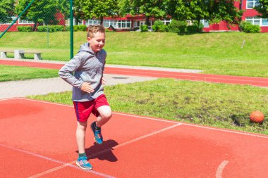 Basketbolcu çocuk sahada esneme hareketleri yapıyor. Çocuk ısınıyor. Güneşli bir günde Red Court Sokağı 'nda..