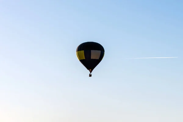 Hot Air Balloon flies on a blue sky.One Blue yellow hot air balloon in blue clear sky.Copy space.